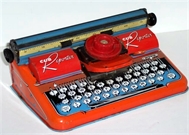 Photo of a bright red stamped metal Cohn Cub Reporter toy typewriter with circular letter index wheel.