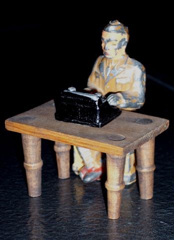 A photo of a Barclay cast metal typing soldier at a typing table with a small typewriter.