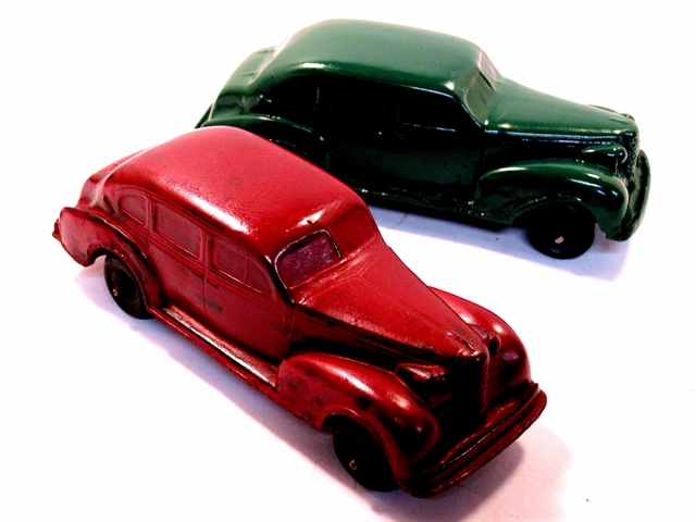 Two 1937 Oldsmobile 4-door sedans, one red and one green.
