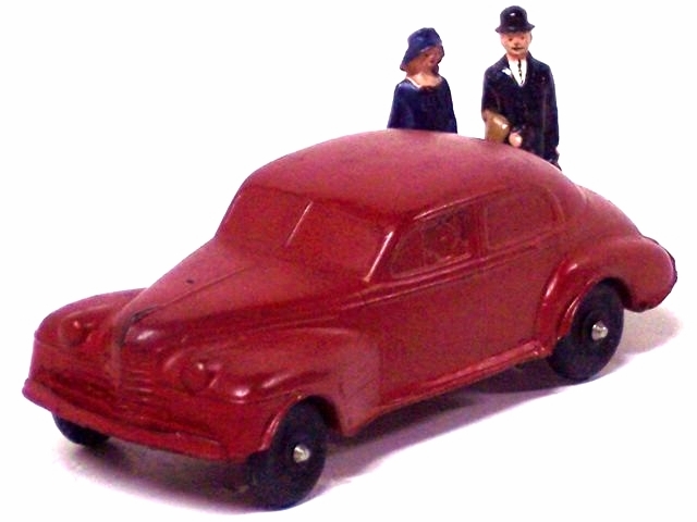 A red '40 Olds with figures of an older man and woman. The car has open fenders, black tires, and is red.