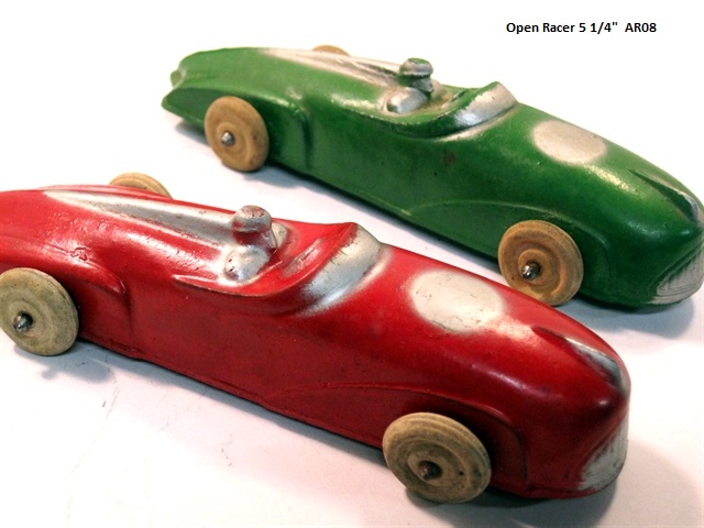 Front quarter view of an unusual red and a green Auburn open racer. They are 5 1/4 inches long, roughly two inches wide and and inch and a half tall. At the rounded front is a silver grill that looks very much like a creepy smile. There is a hood ornament above the grill, also silver, and behind it a round silver circle that looks to be where a number would be painted, though none is. The windscreen and steering wheel are silver, the driver body color with silver highlights. The driver's seat top is integrated into an aerodynamic feature that continues to a point at the rear of the racer. The very rounded front of the car ahead of the driver becomes part of the low, almost flat back of the car. There are raised front wheel fender panels, and larger rear wheel panels at the rear. The wheels are small and black.