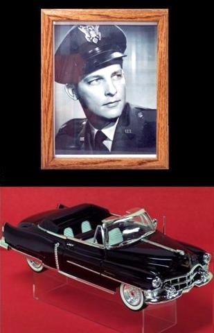 In this picture there is a framed 8x10 photo of Capt. John Payton Jr. in uniform above a black 1:24 scale diecast 1953 Cadillac convertible with black and white interior. The two are the curator's parents.