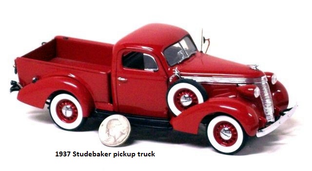 This is the photo of a beautiful red 1937 Studebaker pickup truck taken from the front right. The red is set off wonderfully by the wide whitewall tires. A U.S. quarter is leaning against the side of the truck to give a sense of size to the viewer.