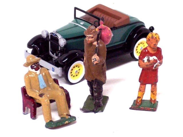 This photo has a Model A roadster behind three figures. The first is a black gentleman wearing a tan hat and suit over a white shirt and green sweater vest. He also sports a necktie, and handkerchief, all of which makes him clearly a gentleman at his leisure as he sits on a bench. The second is a hobo with his worldly goods in a bag hanging from a stick over his shoulder. He is wearing a brown fedora and overcoat with black pants and shoes. The third is a blond-haired little girl in a short-sleeved red dress with scoop collar, high yellow stockings and red shoes. She has blond hair and is holding a little black and white dog in her arms.