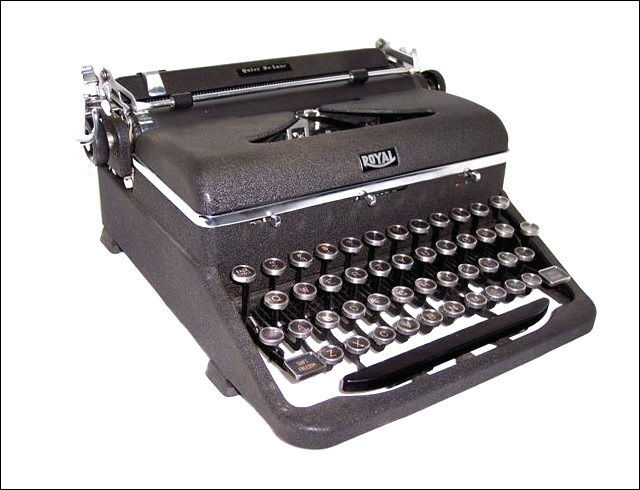 This left front quarter view of the '46 Quiet Deluxe shows the charcoal gray crinkle finish paint, the Quiet Deluxe name on a raised plastic oval on the paper tray, and the Royal logo front and center on the spool cover. Also, the rectangular shift key marked Shift Freedom, and the carriage return lever, and the platen roller. There is a chrome paper guide at the left end of the paper table.