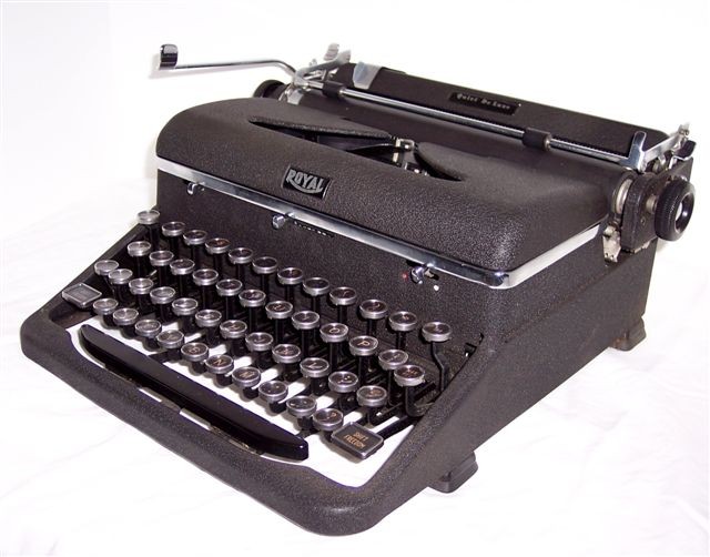 This right front quarter view of the '46 Quiet Deluxe shows the keyboard with its metal ring keys, white letters on black background, and the narrow, rounded chrome band around the base of the ribbon cover. Also, top center on the front of the case is the pressure selector, and to its right the three-position ribbon color selector. The right platen twirler is also shown as well as the paper bail with the lever at the right end and its two rubber rollers.