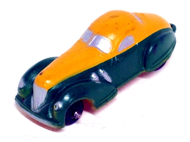 The same model, in yellow over dark green, viewed from the left front. The front windscreen is two pieces, rounded at all corners but the lower inner corners, which come to a sharp point. The top and bottom edges are rounded upward. The rear window is also two piece, longer rather than wide, very round at the end, and pinched at the top of the middle divider. The bottoms come together in a downward point at the divider.