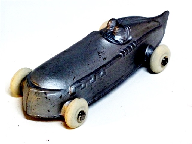 The left front view of the pre-war open racer, painted silver, with large white tires.Four and a quarter inches long. 