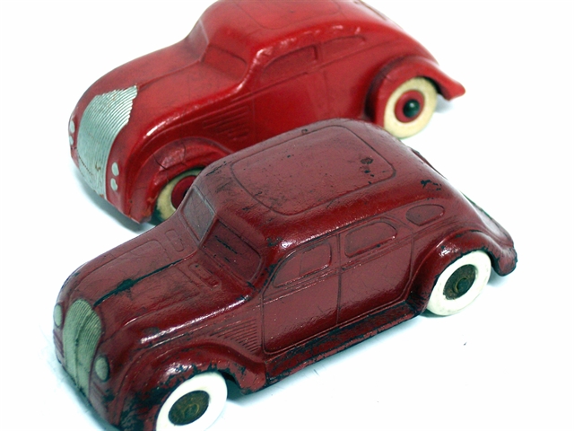 This is a front quarter view of a 1934 DeSoto and a 1934 Chrysler Airflow. The DeSoto is deep maroon, and the Chrysler is deep red. Both are two door sedans.